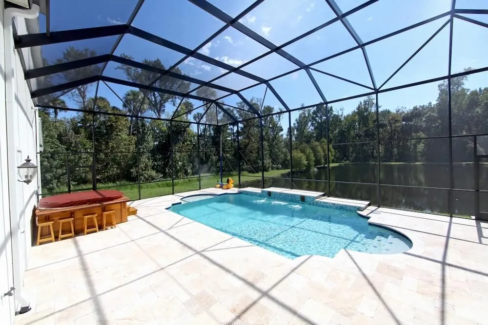 Screened pool and spa enclosure overlooking a pond and trees