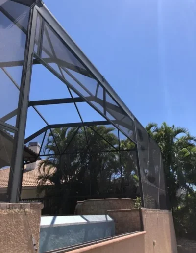 A screened in area with palm trees in the background
