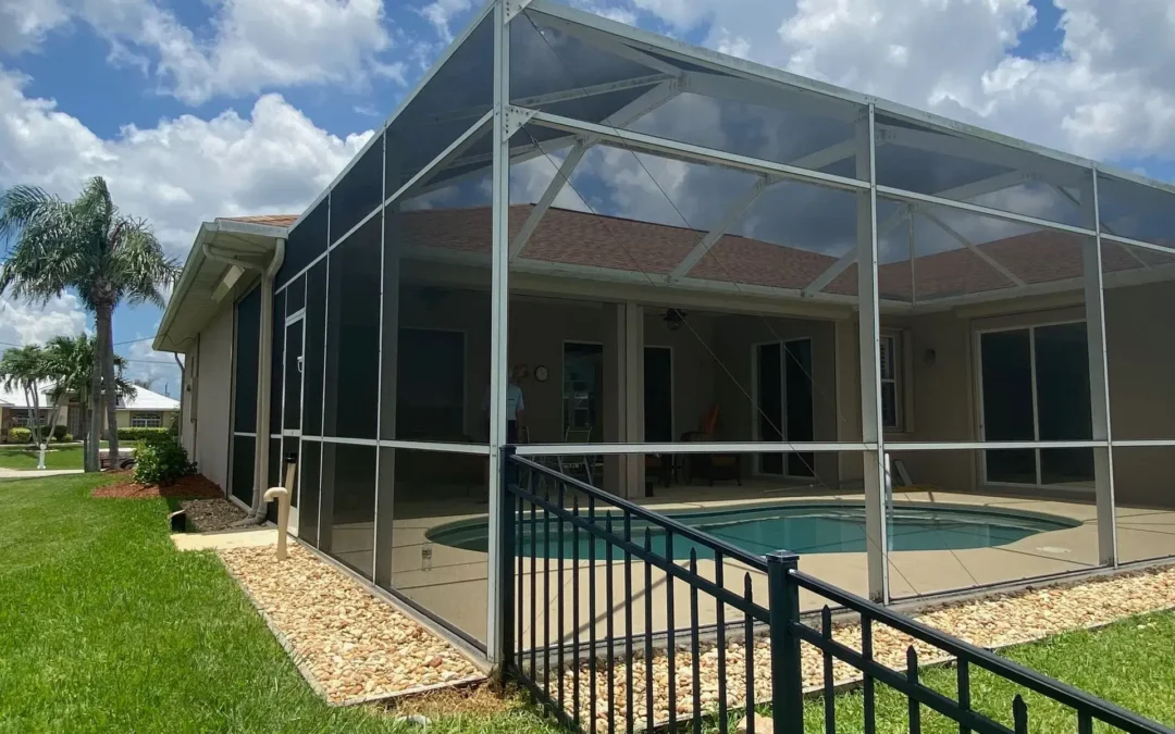 A house with a screened in pool and a fence around it.
